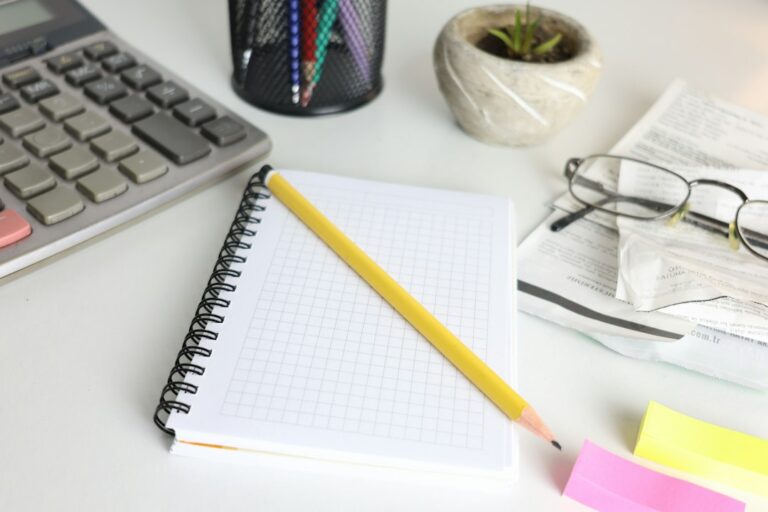 Calculator, notebook, pencil and glasses on a desk