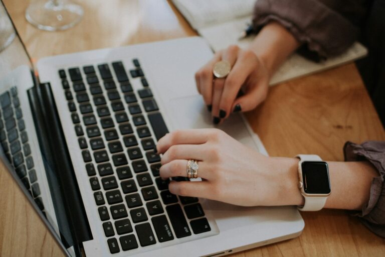 Person writing at a desk beside a laptop